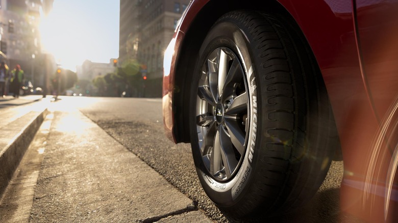 Press image of Defender 2 all-season tire mounted on red passenger car.