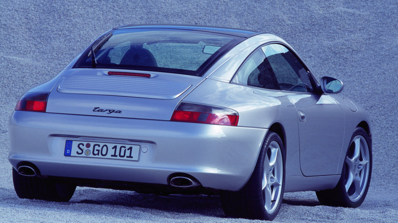 rear three-quarters shot of a silver 911 Targa parked on gravel in front of a big pile of gravel