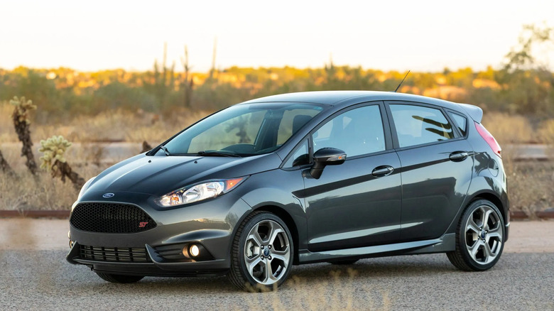 Front three quarters shot of a dark gray Fiesta ST parked on asphalt in front of a desert sunset