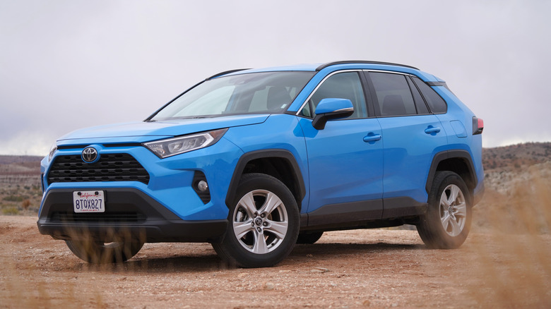 A blue Toyota RAV4 parked in dirt.