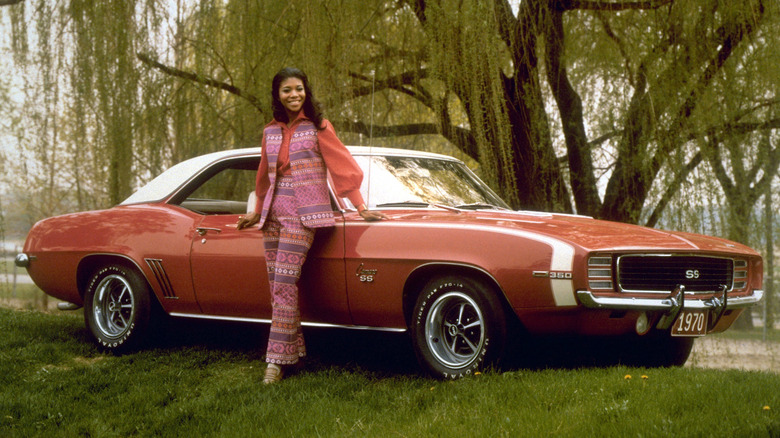 A woman standing in front of a Chevrolet Camaro SS 350