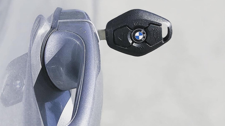 A close-up photo of a diamond-shaped BMW key in the door lock of a silver car