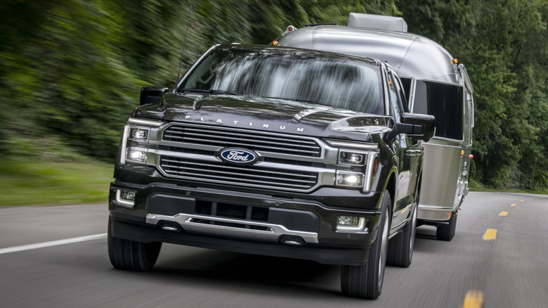 Black 2024 Ford F-150 Platinum trim pickup truck seen from front towing an Airstream-style trailer