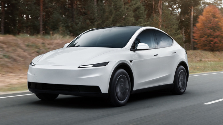 White Tesla Model Y Standard front left view driving on a road in autumn