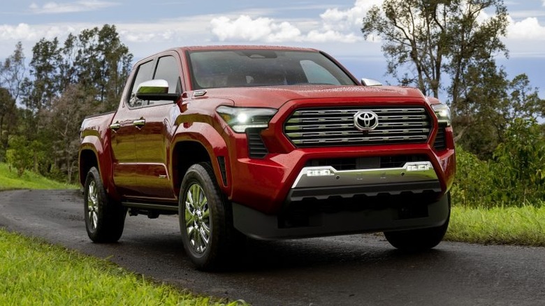 Red 2024 Toyota Tacoma pickup truck front right view seen driving on a scenic road