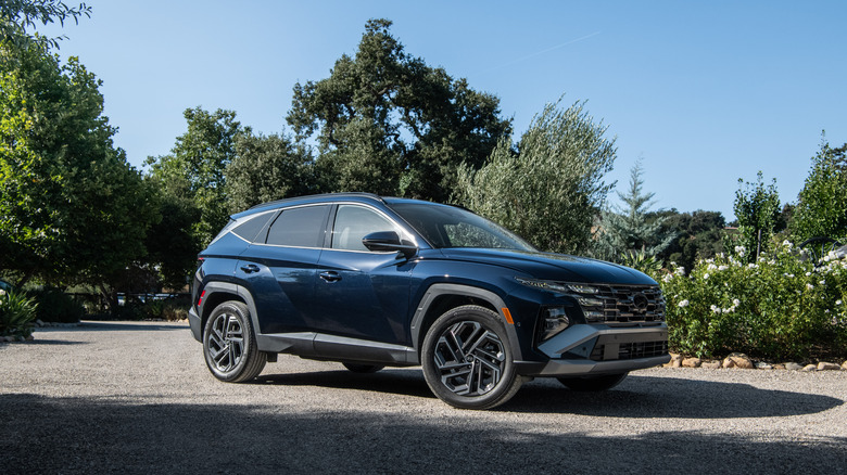 A blue 2026 Hyundai Tucson Hybrid parked on a gravel road.
