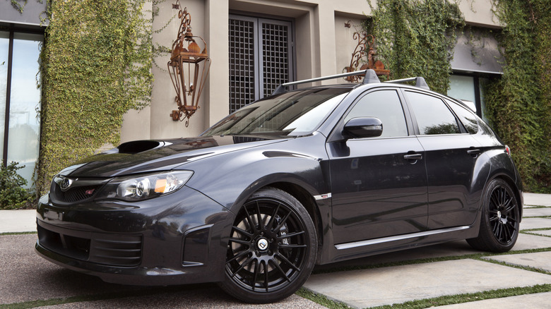 Black Subaru WRX STI wagon with aftermarket wheels parked outside