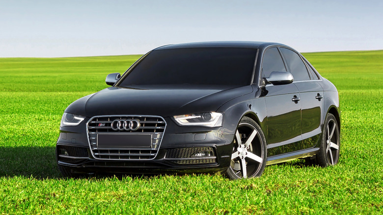 Black Audi S4 sedan parked on green grass with clear blue sky