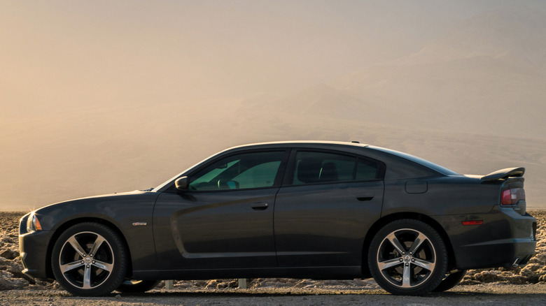 Dark Gray Dodge Charger sedan on dirt road at sunset