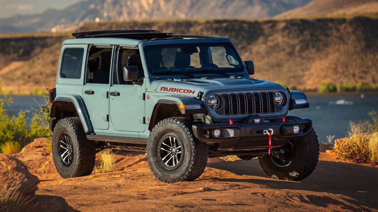 A blue Jeep Wrangler Rubicon parked in the desert in front of a lake