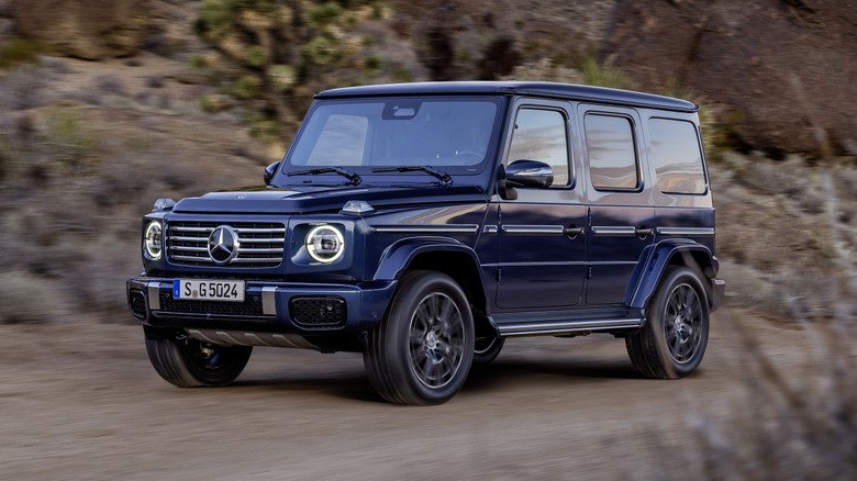 A blue Mercedes-Benz G-Class G-Wagen driving on a dirt road