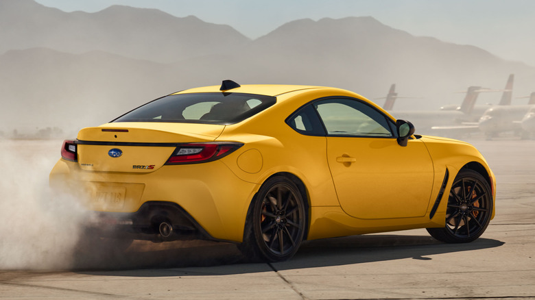 Yellow Subaru BRZ drifts through an airfield.