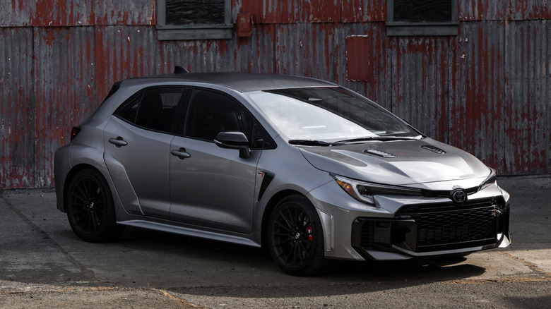 A silver Toyota GR Corolla parked in an old industrial park.