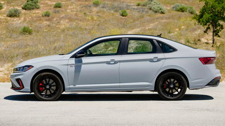 A Jetta GLI parked against a grassy hill background.