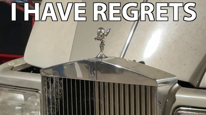 The front grille and opened hood of a broken beige Rolls Royce of the early aughts era with the title font "I HAVE REGRETS" in all-caps across the top.
