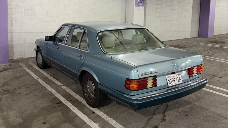 Rear 3/4 view of a teal Mercedes-Benz W126 S-Class in a parking garaga