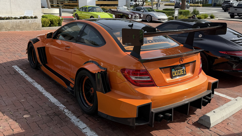 Rear 3/4 view of an orange Mercedes C63 with a body kit