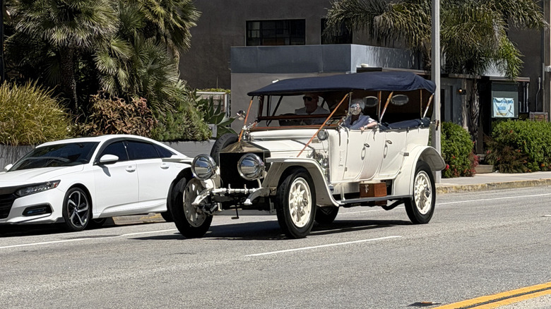 An old white Rolls-Royce driving