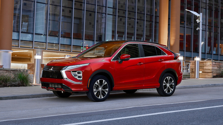 A red, Mitsubishi Eclipse Cross on a street in front of a glass office building.