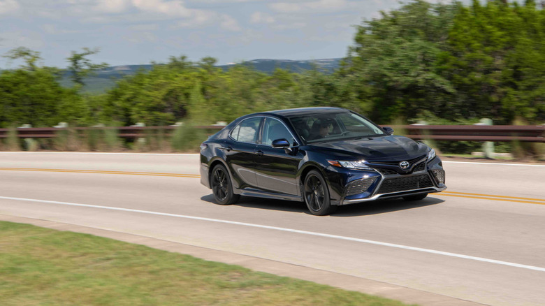 The 2022 Toyota Camry appliance in dark blue on a sweeping highway curve.
