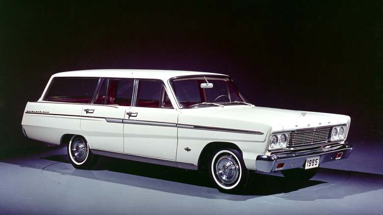 A white, 1965 Ford Fairlaine 500 wagon on a grey surface with a black background.