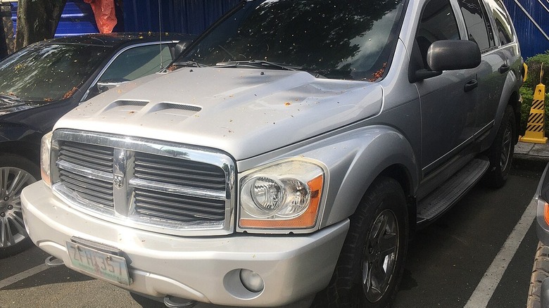 A dirty rusty silver second-gen Dodge Durango parked in a lot