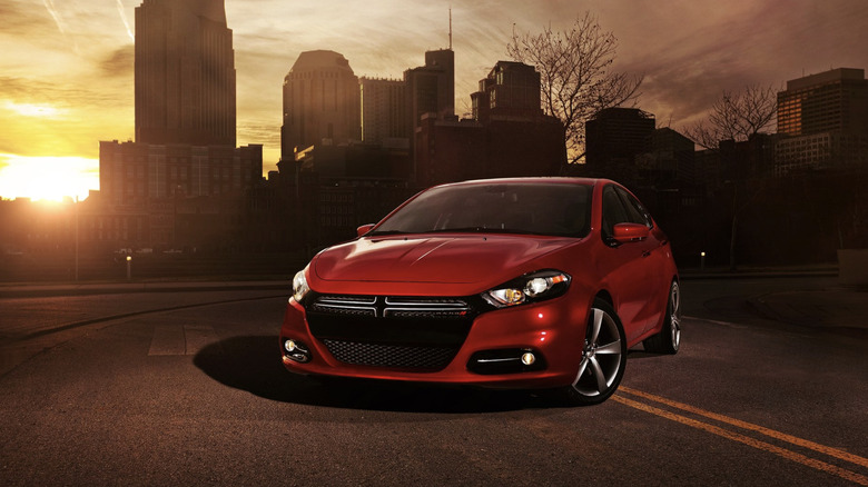 A dodge dart apparently at the end of the world. It's parked across a road with a darken cityscape behind it