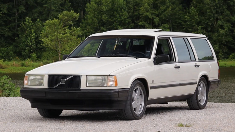 A white Volvo 740 wagon parked in front of some trees