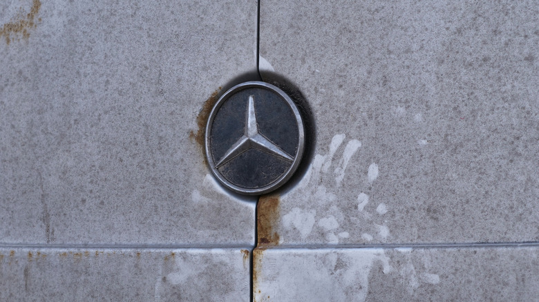 A mercedes-benz emblem covered in dust and rust