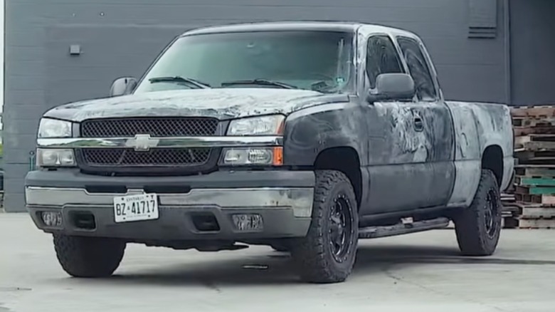 A pickup truck getting repainted, it's black body all scuffed up ahead of priming