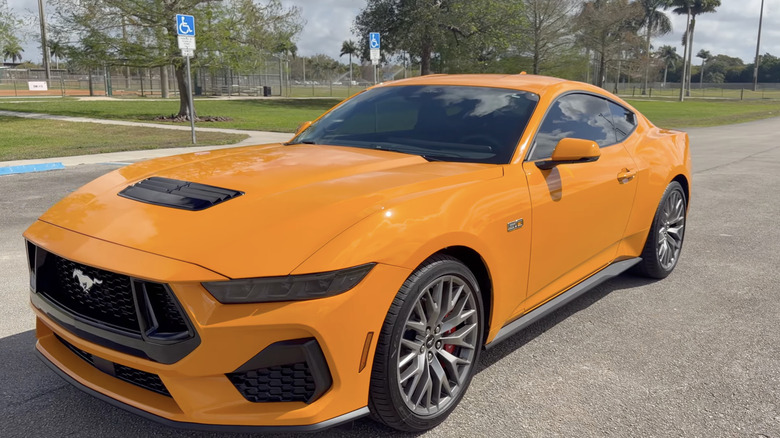 An Orange Fury Mustang Ford Mustang parked in a parking lot on a cloudy day