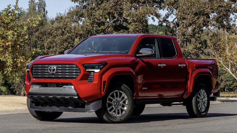 a red 2024 toyota tacoma parked in front of trees