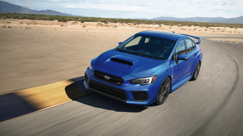 A blue WRX STi driving around a track in the desert.
