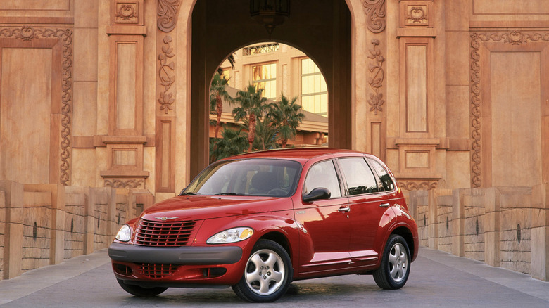 A red PT Cruisers parked outside of a sandstone facade