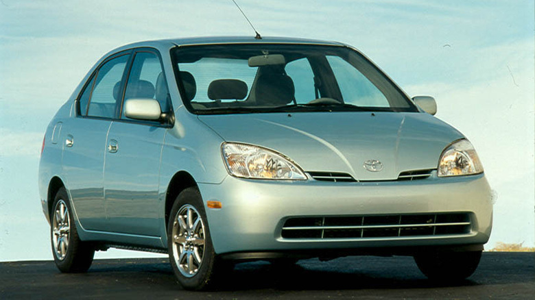 Front three quarters shot of a light blue 2001 Prius parked on blacktop in front of a blue sky