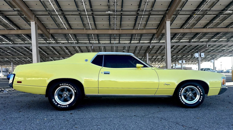 A yellow 1971 Mercury Cougar XR-7 Hardtop Coupe under an outdoor canopy-like structure.
