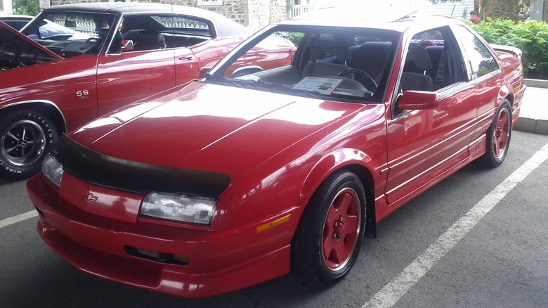 A close-up of a red 1991 Beretta GTZ  in a parking lot for a car show.