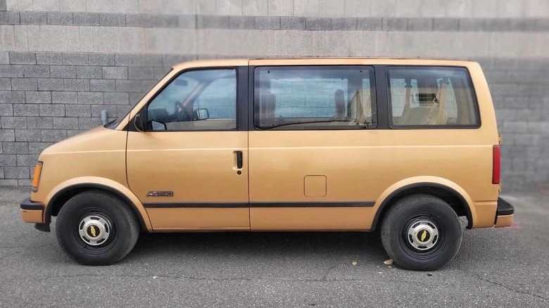 The quintessential gold Chevrolet Astrovan with black accents in an industrial setting with brick background.