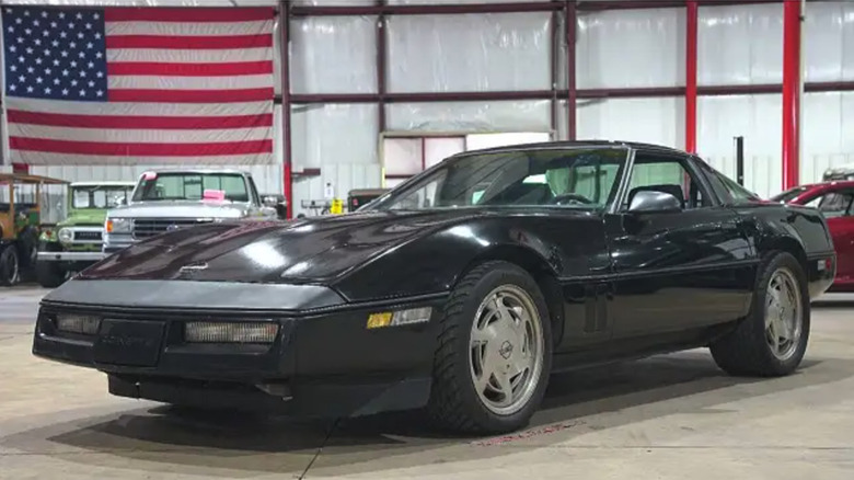 A black 1986 Chevrolet Corvette with hard top, set in a garage.