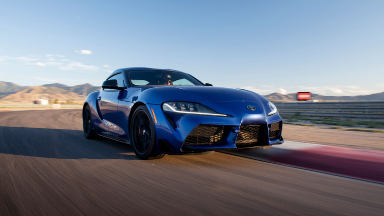A blue Toyota GR Supra driving around a race track