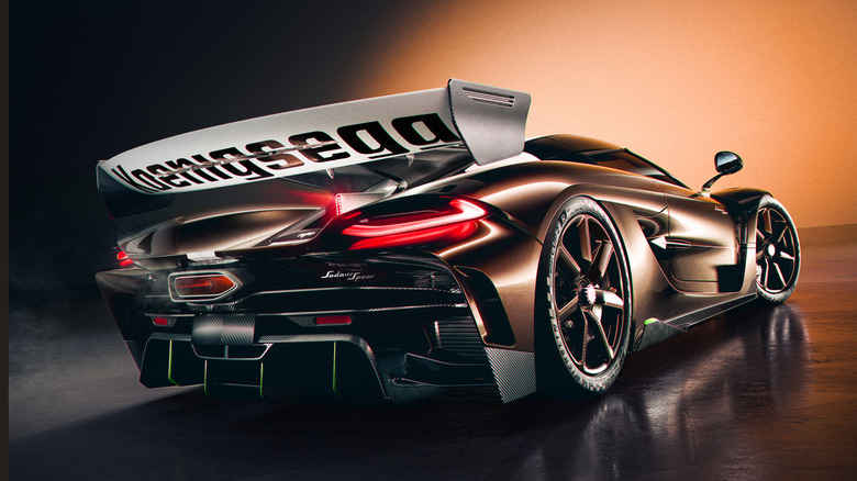 Rear three quarters shot of a brown Koenigsegg Sadairs Spear parked in a studio in front of an orange backdrop