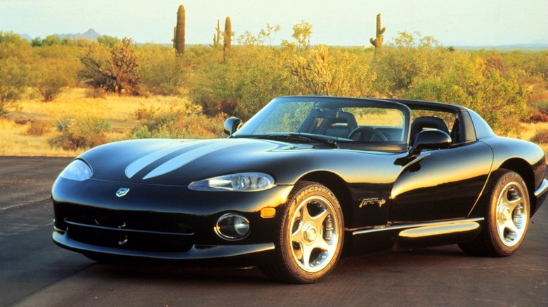 Front three quarters shot of a black Viper with silver stripes parked on blacktop in front of a desert landscape with cactus and shrubs