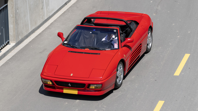 A red Ferrari 348 TS driving down a city street