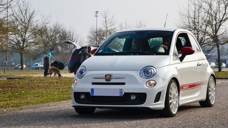 A white Fiat 500 Abarth driving down a park road.