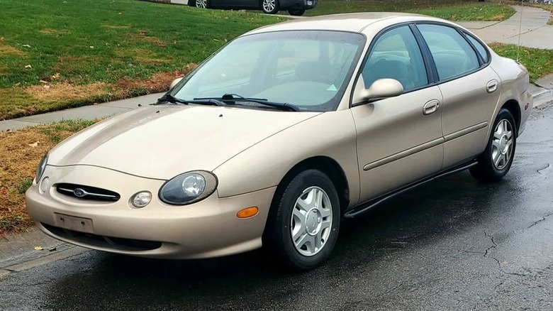 A beige Ford Taurus parked on a residential street