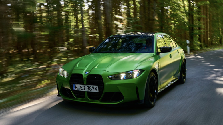 A bmw m2 driving down a forested road