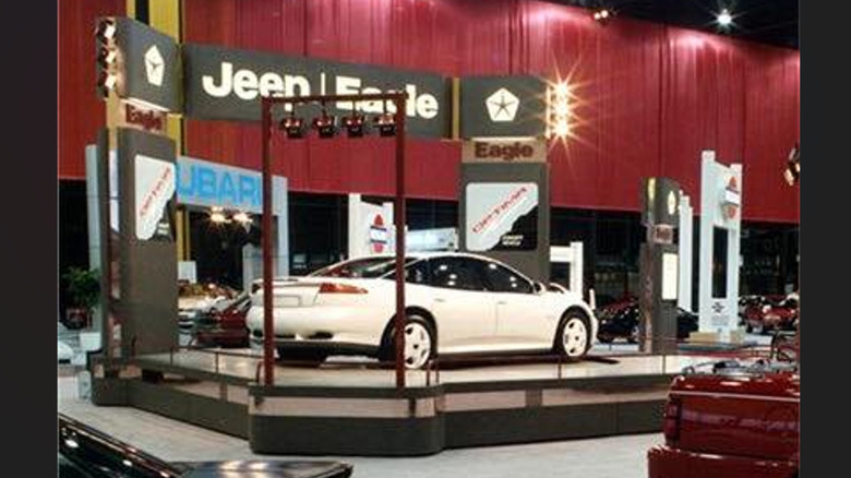 rear three-quarters wide shot of the Eagle Optima concept car at the auto show in front of dark red curtains in the Jeep Eagle booth