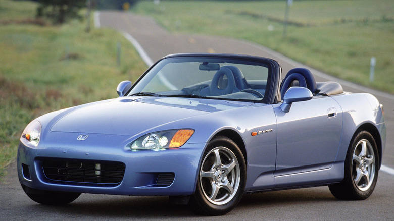 Front three quarters shot of a light blue 2002 S2000 parked on a pull-out on a two-lane road flanked by grass