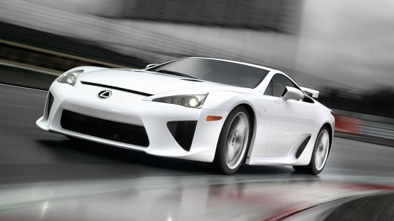 A front three quarters shot of a white LFA driving around a corner on a wet racetrack