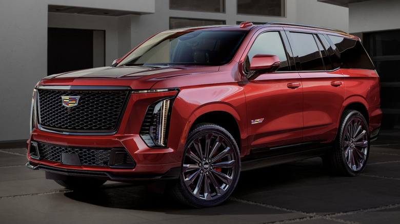 A dark red Cadillac Escalade V parked outside a house.